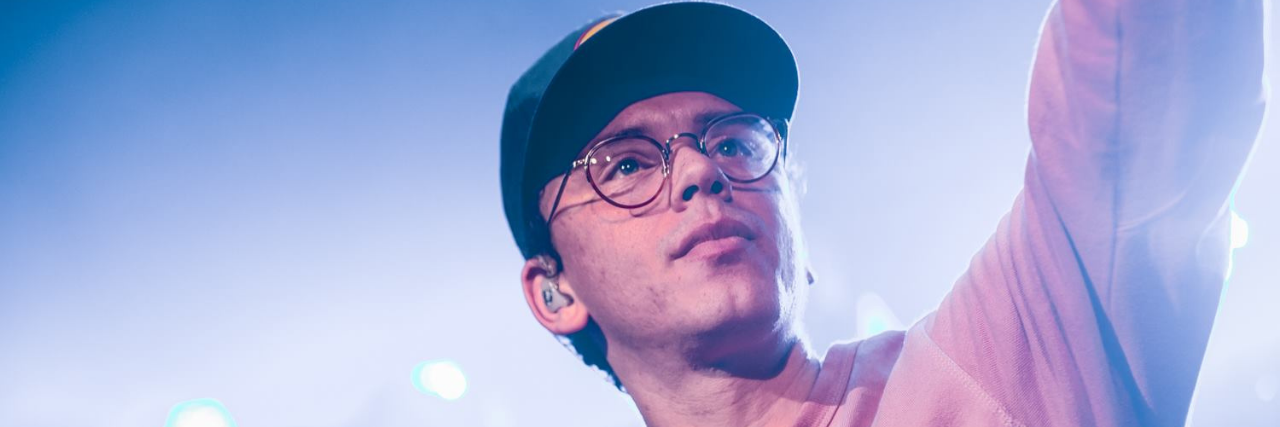 The rapper Logic on stage looking up, raising his arm