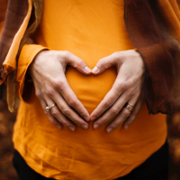 photo of a pregnant woman holding her hands on her belly in the shape of a heart