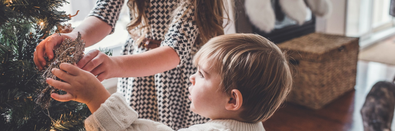 Powerful Lessons at the Holidays as an Abuse Survivor Two young children putting ornaments on a Christmas tree