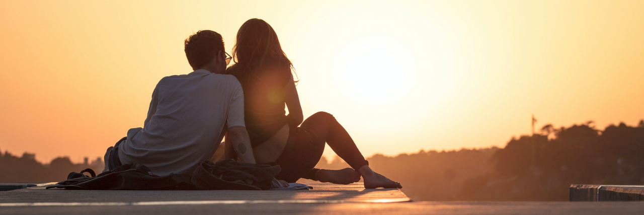 A couple sitting on a rooftop at sunrise