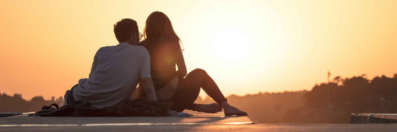 My Partner and I Had to Break Up Because of Our Mental Illnesses A couple sitting on a rooftop at sunrise