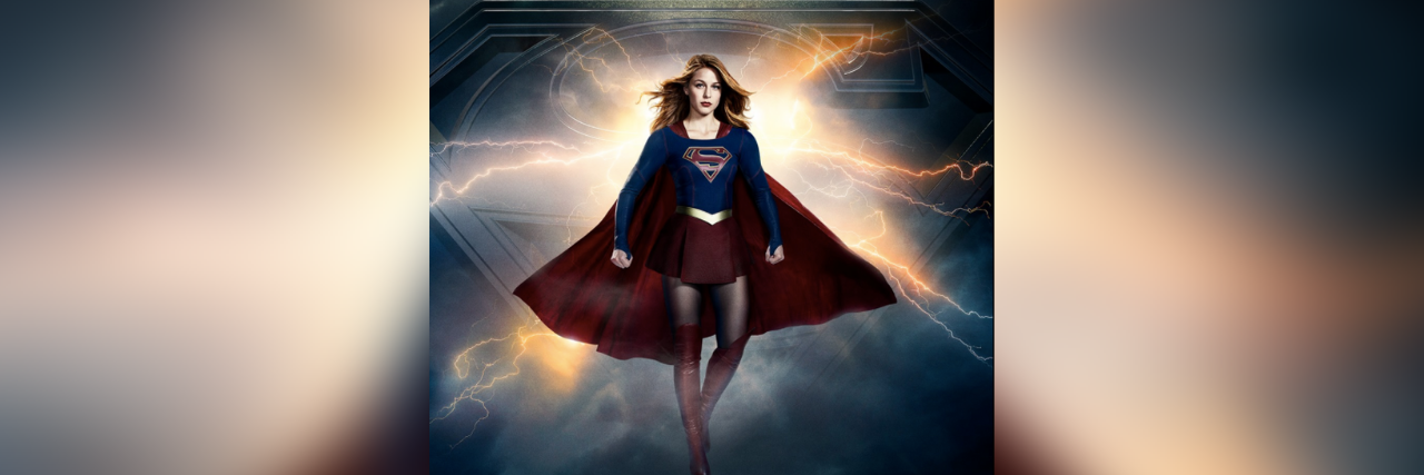 Supergirl wearing red cape in front of stormy sky