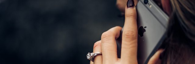close up photo of someone with a phone raised to their ear, engagement ring on their finger