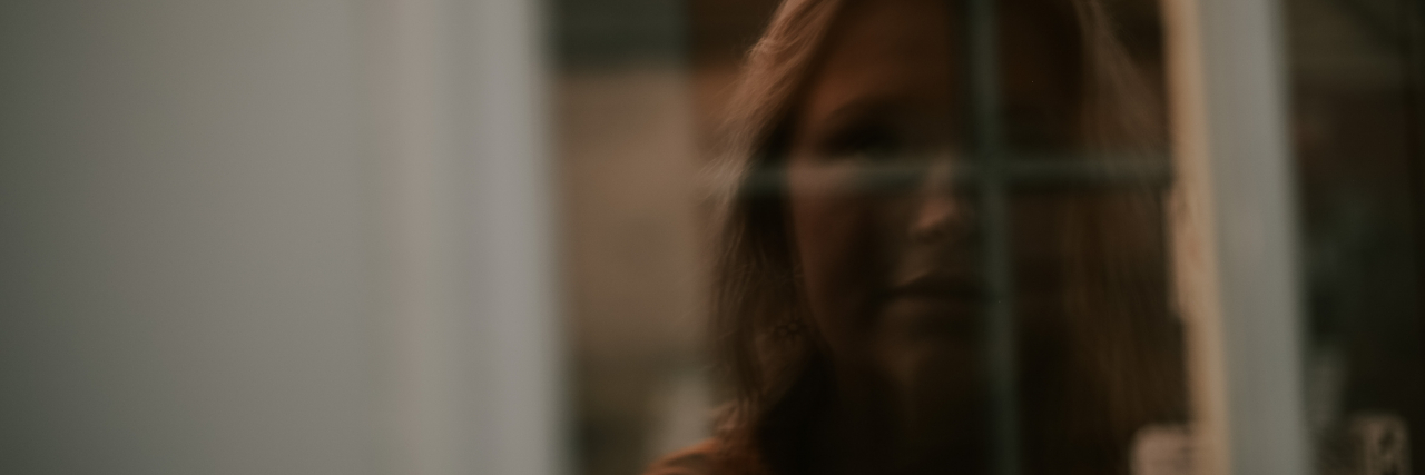 photo of a woman's scared reflection in a window