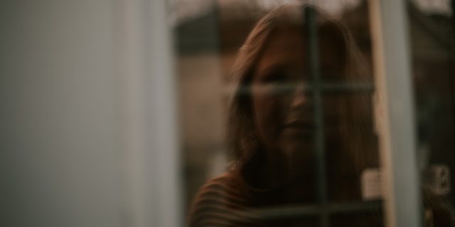 photo of a woman's scared reflection in a window