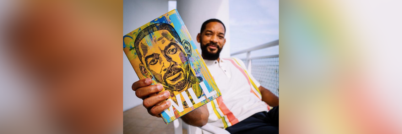 Exploring Will Smith's 'Psychosomatic Reaction' to Orgasm in Memoir Will Smith holding a copy of his book "Will" sitting on a porch with blue sky in the background