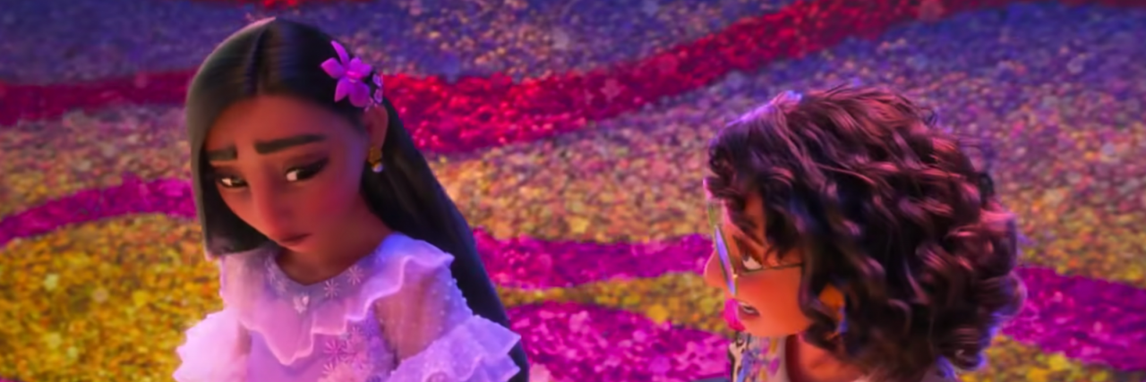 Isabela Madrigal from Disney's "Encanto" stares at her younger sister sadly, with pink, purple, yellow, and red roses all around them. She wears a flower in her hair and a purple dress, while Mirabel wears a white shirt on the right of her.