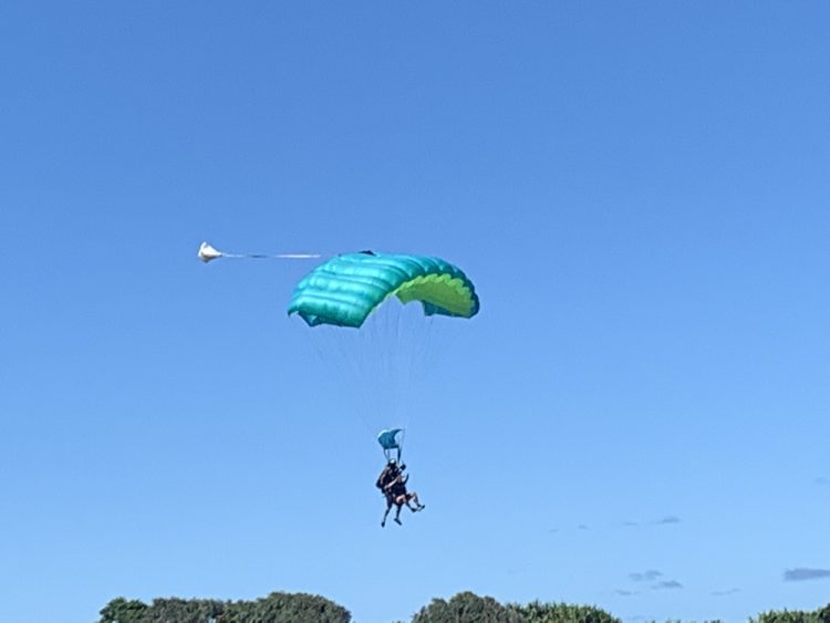 A macro shot of the two men landing with a green parachute above them