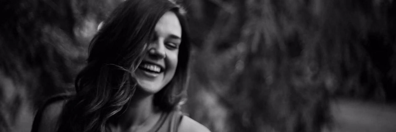 A black and white photo of the author's daughter, smiling with her eyes closed