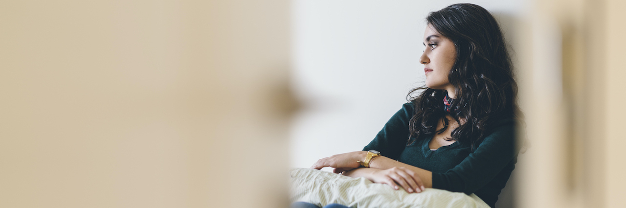 Woman sitting alone in room, hugging a pillow