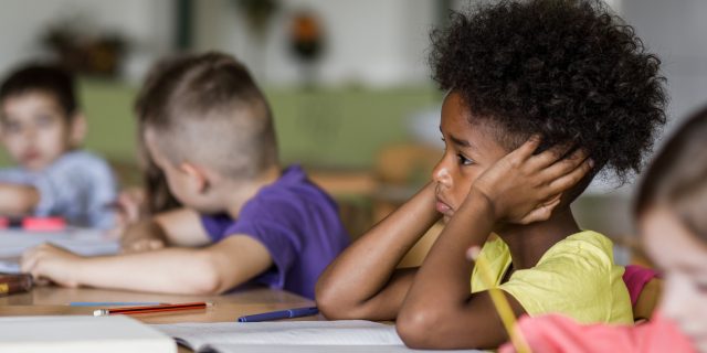 Sad Black child in classroom.