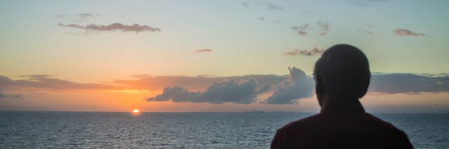 Man watching moody sky sunset aboard boat.
