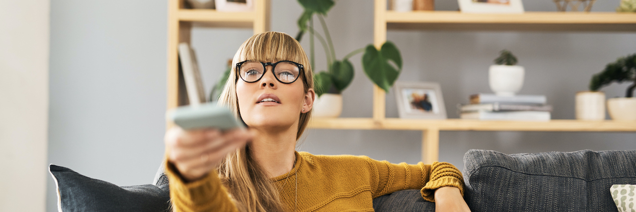 How Movies Help Me Understand and Express Emotions With Alexithymia Woman pointing remote towards television on the sofa at home