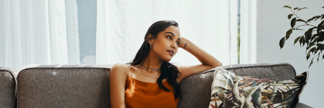 Advice for People Newly Disabled Due to COVID-19 Woman looking thoughtful while relaxing on the sofa at home