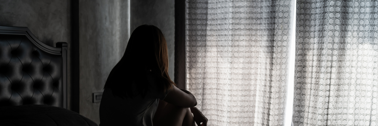 How My Autism and Surviving Sexual Abuse Intertwine Sad woman sitting at the edge of bed.