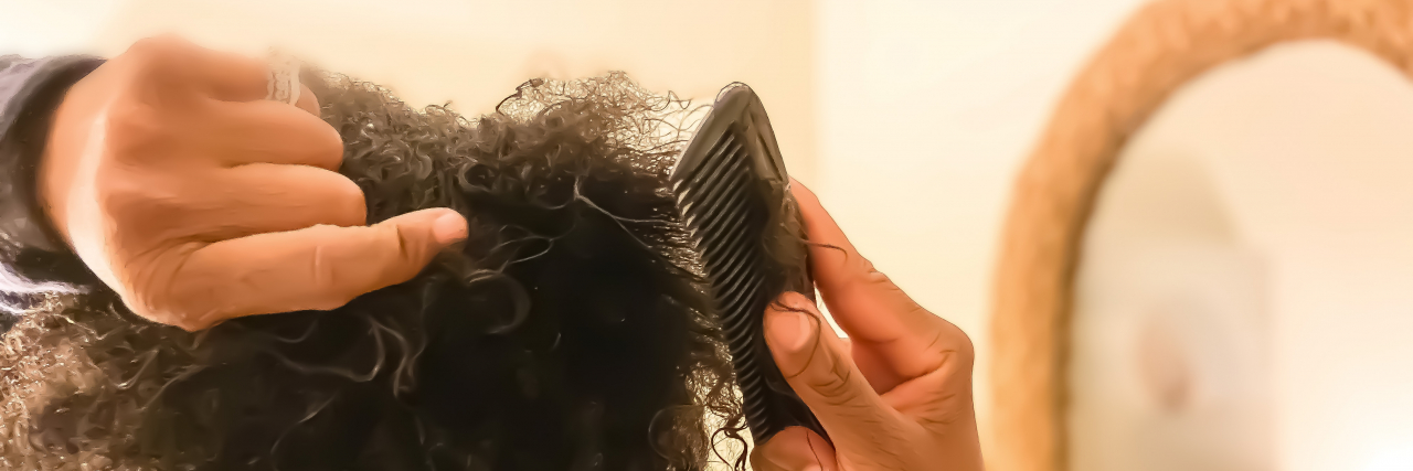 Black woman combing natural hair.