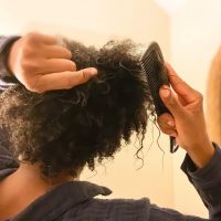 Black woman combing natural hair.