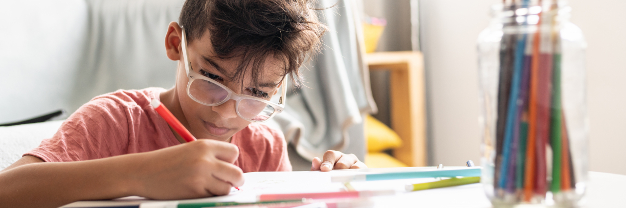 When I Was Asked What's 'Wrong' With My Son With a Disability Boy drawing at a coffee table.