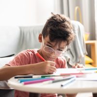 Boy drawing at a coffee table.