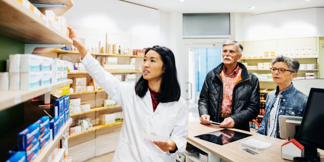A pharmacist helping a mature couple fill prescriptions at local pharmacy..