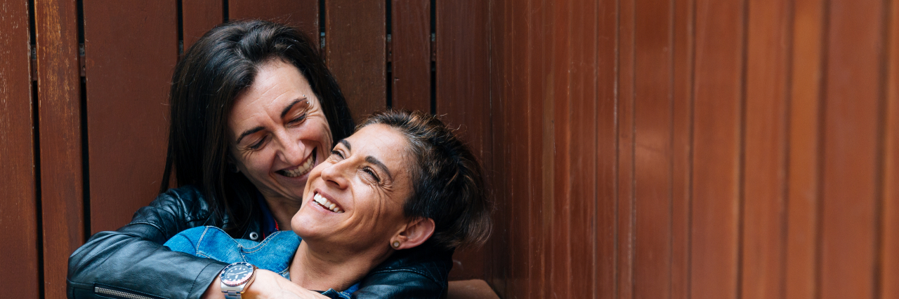 Keeping a Long-Term Relationship Strong With Chronic Illness Happy middle aged lesbian couple embracing.