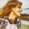 Smiling curly hair woman with large headphones walking outdoors.