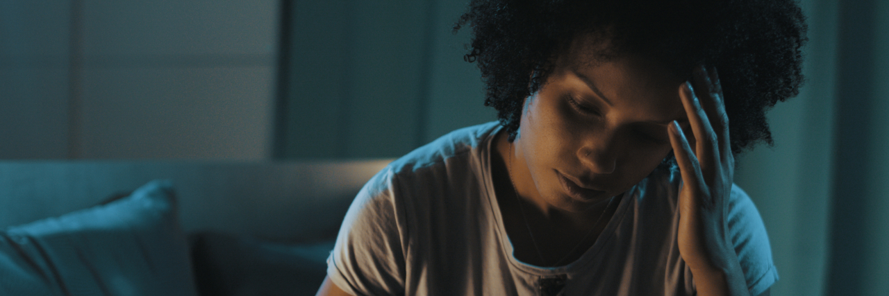 What Living With Agoraphobia and Panic Disorder Is Like Woman sitting on the side of her bed, exhausted