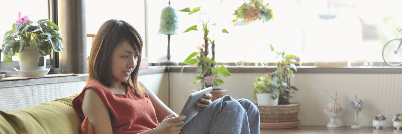 Why Assessing My Screen Time Is Complicated as a Disabled Person Woman looking at a digital tablet in living room.