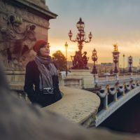 Woman with a camera around her neck standing on Pont de la Concorde in Paris in morning.