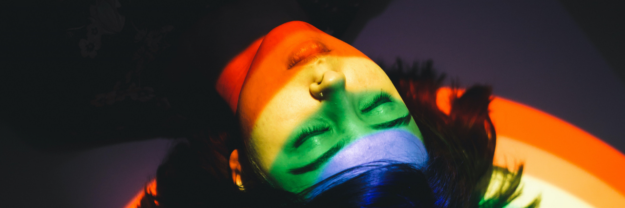 Woman laying with eyes closed and light from rainbow over her face