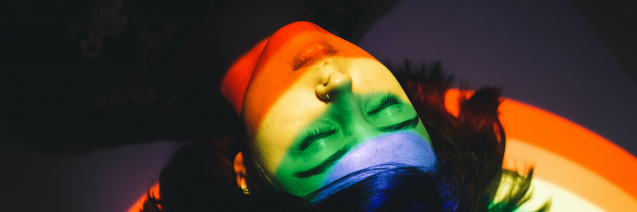 How My OCD Relates to My LGBTQIA+ Identity  Woman laying with eyes closed and light from rainbow over her face