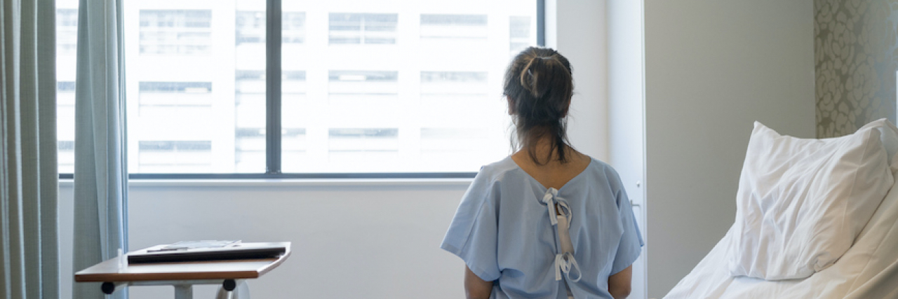 Checking Myself Into a University Clinic for Mental Illness Rear view of woman sitting on bed in hospital room, looking out window