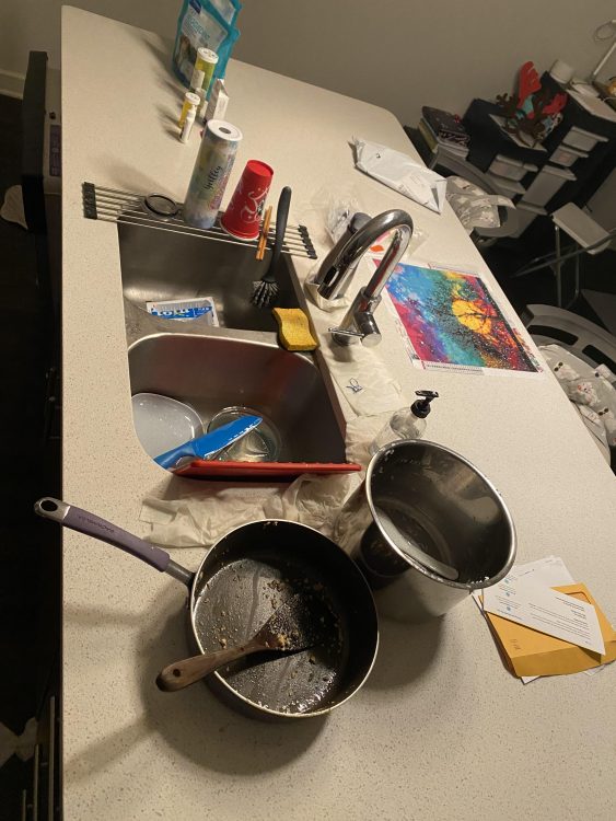 A messy kitchen counter with pots and pans and letters out.