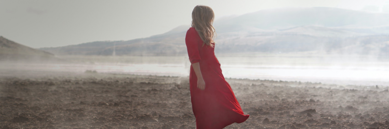The Grief That Comes Naturally When Your Life Is Changed by Illness A woman standing in a field of dirt