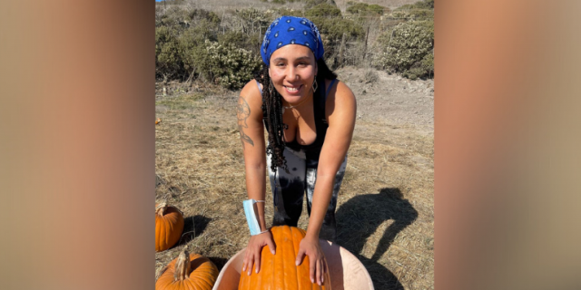 Photo of contributor in field with a wheelbarrow and pumpkin