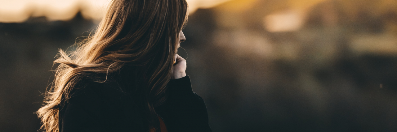 Trauma and Endometriosis: Don't Shame Me Because I Don't Have Children photo of a woman standing in side view looking out over a bridge