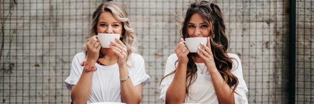 Two women sipping from coffee mugs