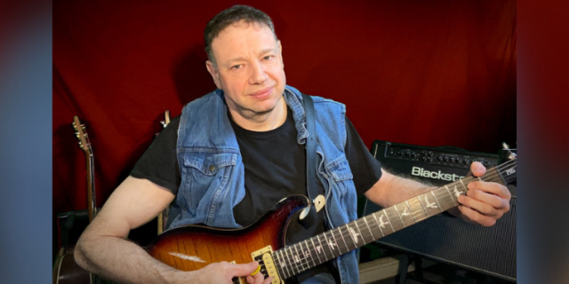 Photo of musician Jason Didner holding a guitar