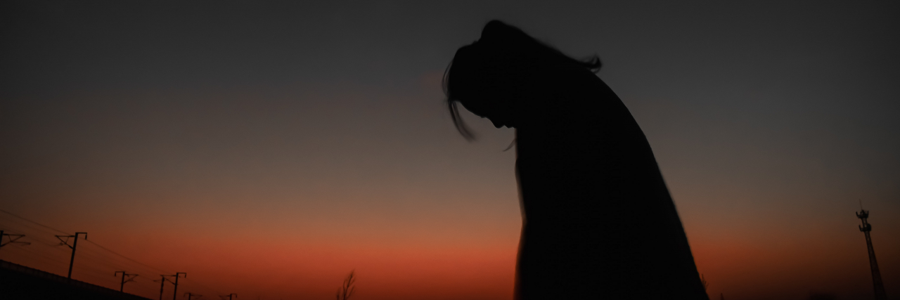 I Feel Alone With Borderline Personality Disorder, but Can't Reach Out Silhouette of a woman looking down, outside at sunset