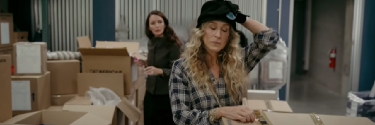 Carrie opening boxes with Charlotte in the background from "And Just Like That..."