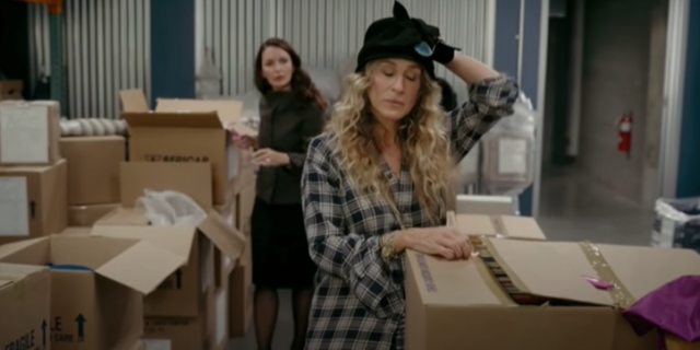 Carrie opening boxes with Charlotte in the background from "And Just Like That..."