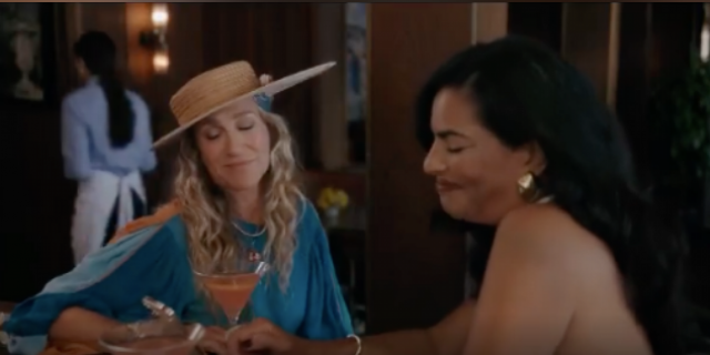 Image of Carrie and Seema from "And Just Like That..." sitting together to have a drink