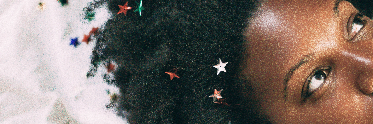 Yes, Black People Can and Should Go to Therapy Too close up photo of a woman lying on a white cloth surfce with small stars in her hair