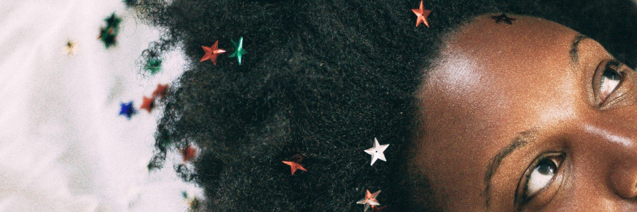 10 Things You Should Know About Minority Mental Health close up photo of a Black woman lying on a white cloth surface with small stars in her hair