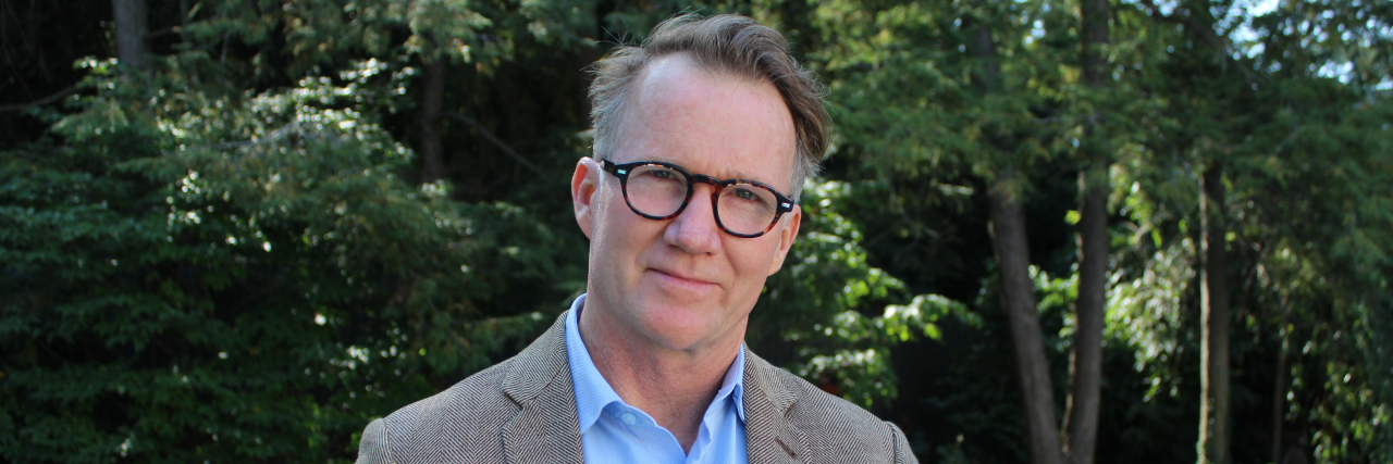 How Ignoring My Mind Instead of Fighting It Helps My Depression Middle-aged man in a collared shirt and sports jacket with glasses looking into camera