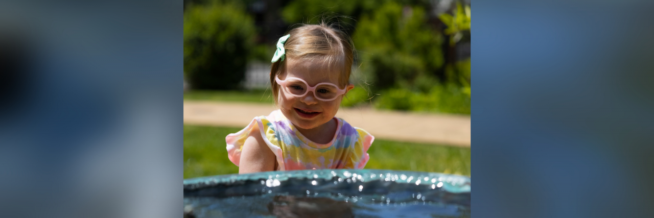 Please Teach Your Kids to Accept Their Classmates With Disabilities Nicole's preschool daughter who has Down syndrome looking into a pool.