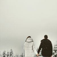 Back of a man and woman in winter jackets holding hands