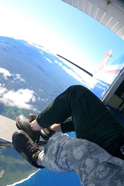 An aerial view of a two men's feet dangling out of an airplane