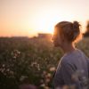 Young woman in a field looking away at sunset