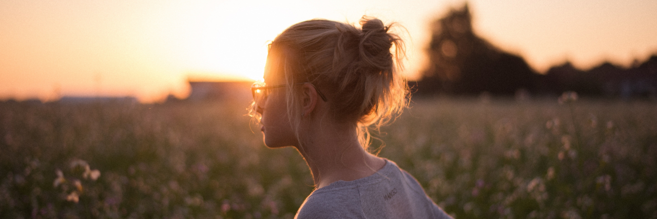 The Cycle of OCD: Does It Help or Hurt? Young woman in a field looking away at sunset